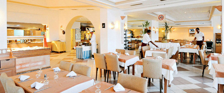 Im Hotel Meninx bereitet Service und Küche den Restaurantbereich in freundlicher, gemütlicher Atmosphäre vor, während helle mediterrane Gestaltung für ein einladendes Ambiente sorgt.