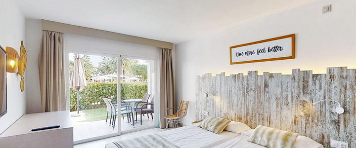 Das helle, freundliche Doppelzimmer in moderner Gestaltung mit Holzelementen und beiger Farbgebung öffnet den Blick auf die angrenzende Terrasse.